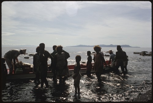 People on beach taking goods to a boat