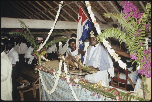 Holy Mama in church with plant decorations, and sculpture of a winged figure