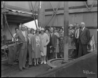 Group portrait of men and women on the drill floor of an oil well, probably at the Venice or Playa del Rey oil field, Los Angeles, circa 1930