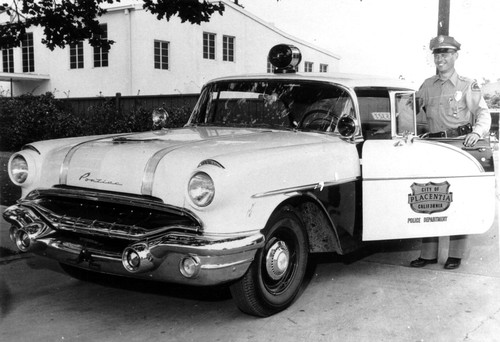 Photograph of Sergeant Dean Bosche standing at open door of new police car