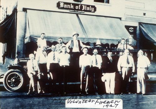 Photograph of volunteer firemen standing in front of fire engine