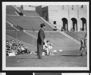University of Southern California head football coach Jess Hill (right) yelling at a football pre-game practice at the Los Angeles Memorial Coliseum, with players and 10-yard markers behind him, 1951