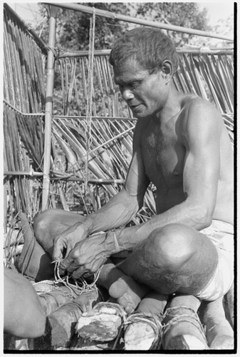 A Kwaio feastgiver strings shell beads into valuables on the platform where he will publicly present them at his feast