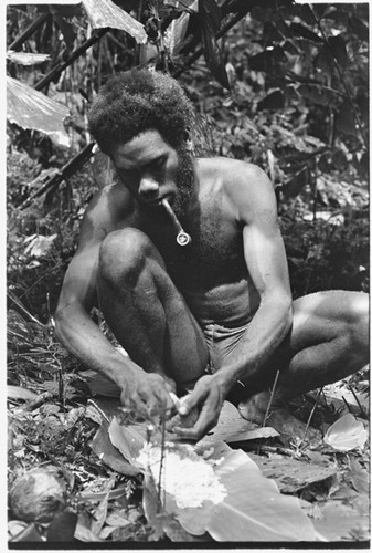 Ubuni scraping coconut meat from shell for ritual pudding