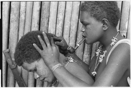 Geninaatoo delousing her sister-in-law Nanaua's hair