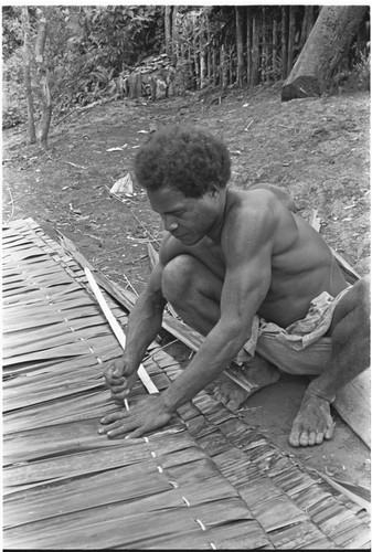 Man sewing thatch panel