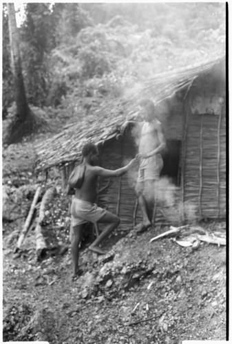 Taaboo hands matala string of ancestor relics to older brother Laete'eboo