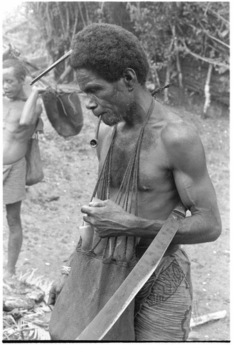 Man standing with bushknife and functional kafa comb in hair