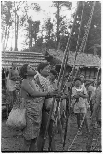 Two women give shell valuables from the ground at mortuary feast at 'Aida in August 1979