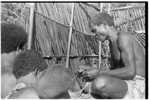 A Kwaio feastgiver strings shell beads into valuables on the platform where he will publicly present them at his feast