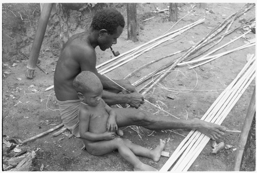 Man shaves split bamboo for use in wall construction