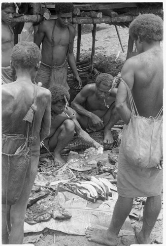 Men cutting up pork, to divide it for a mortuary feast