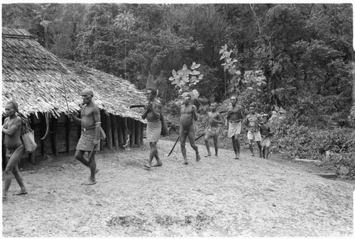 People entering clearing with shell money strings on sticks