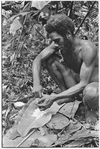 Ubuni scraping coconut meat from shell for ritual pudding