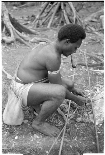 Man untying rolled shell money valuable from display pole