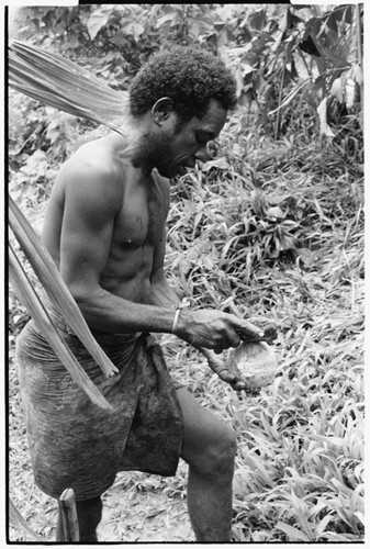 Wiri, high priest for this group, breaks coconut with rock as part of ritual