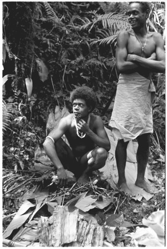 Two men lifting the pudding, which is bundled in leaves