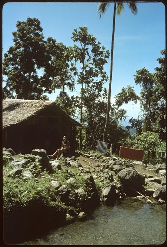 Woman sitting on a rock, in front of building