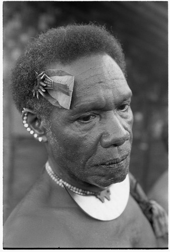 Man with dafi pearshell neck ornament, and plaited fari (spilt) comb with kwaloi'a porpoise tooth star, and leaf bespelled to protect him from sorcery at the feast