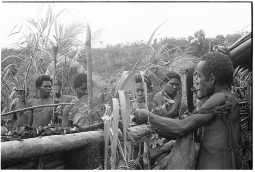 People standing around at the feast; Kwailoboo, 'Elota's younger brother, is at right with machete