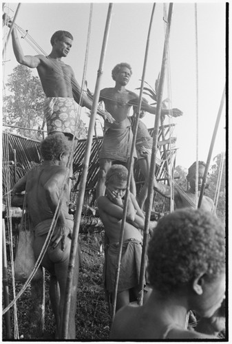 Men on mortuary feast platform presenting red shell money valuables and giving speeches, Dio Joe Bono on left, Geleniu on the right