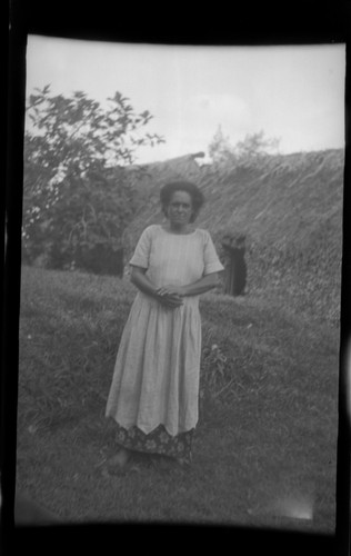 Fijian woman in front of a traditional house