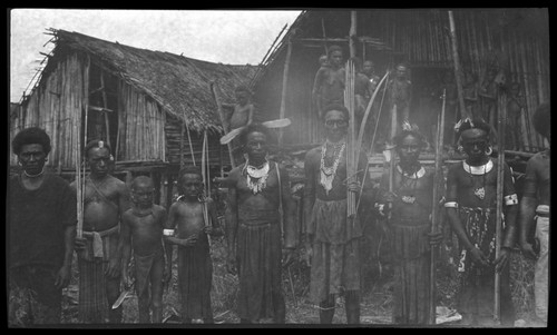 Goaribari men and boys outside houses; some men are wearing kina, a crescent shell valuable necklace