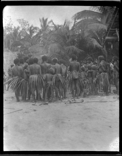 Men and children wearing leaf skirts