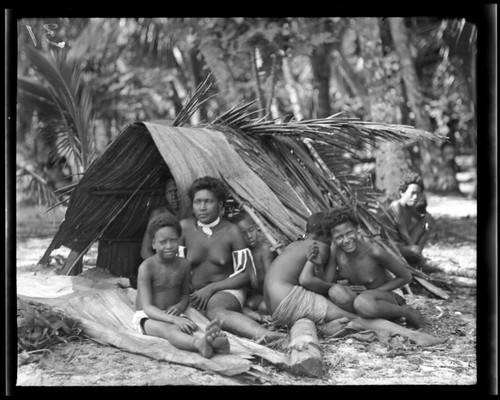 Women and children sitting beside storage tent