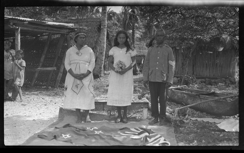 Mana, his wife, and a girl, standing with a New Zealand flag