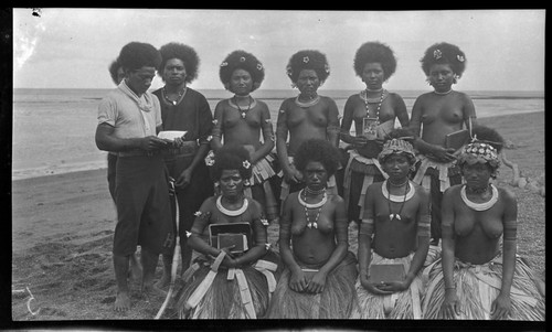 Men and women of Gaile, a Motu village, holding books and photographs; women wearing kina, crescent shell valuable necklace