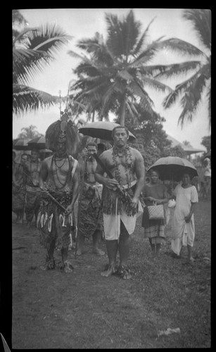 Group of people, two men in front wearing traditional samoan clothing