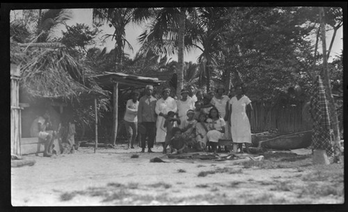 Group portrait by house and canoe