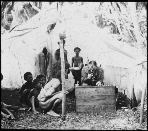 Solomon Islanders observing European man examining a slide through a microscope