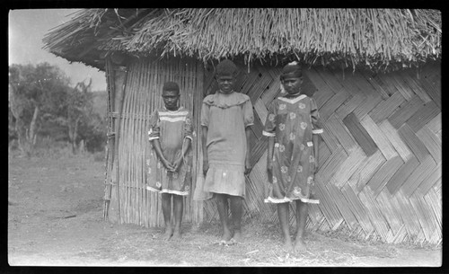 Girls in dresses, outside a house