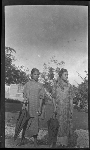 Portrait of two young women holding umbrellas