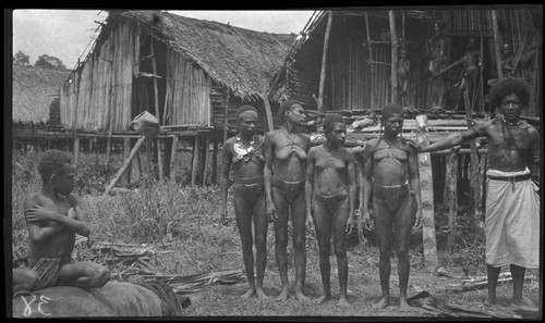 Goaribari people outside houses; woman on left wearing kina, crescent shell valuable necklace