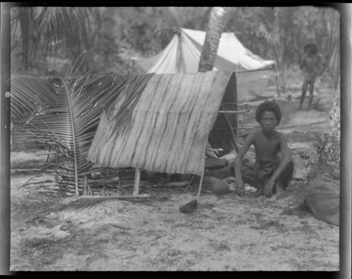 Boy sitting beside storage tent