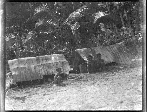 Women and child sitting in front storage tents