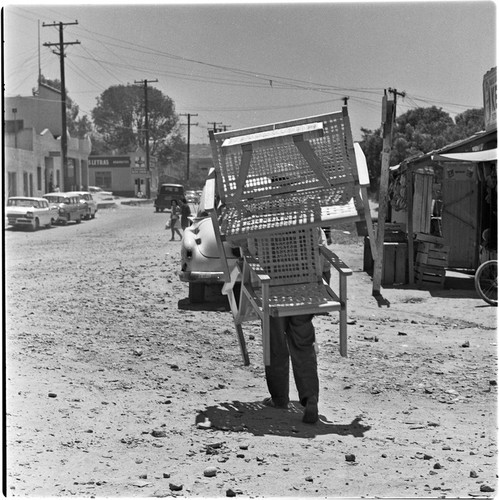 Man carrying wicker furniture down the street