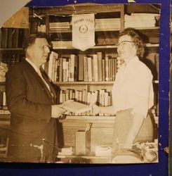 Poster photo of Delbert (Deb) Triggs, president of Sebastopol Rotary, presenting a shelf of books to Helen Pedroia, Librarian of Analy Union High School, 1950s
