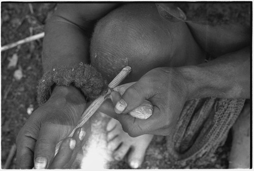 Carving: stone tool being used to smooth an arrow