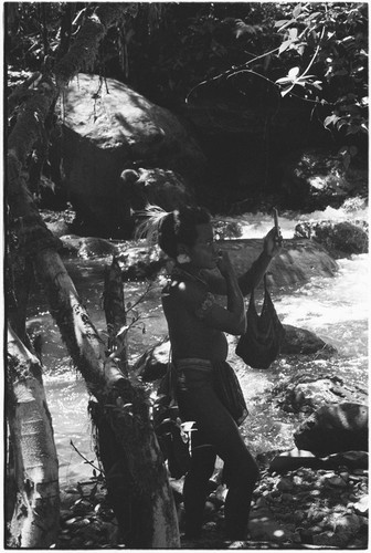 Man on river bank examines himself in mirror