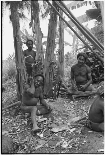 House-building for Rappaports: men smoke, taking a break from sharpening support posts with machetes