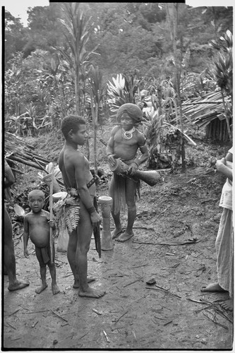 Pig festival, singsing preparations: men with kundu drums beside cordyline plants at men's house