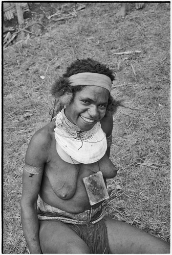 Smiling woman wearing shell valuables, beaded necklace and mirror