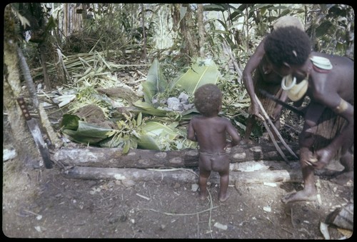 Pig festival, pig sacrifice, Torpai: Kinimp watches Moramp and another woman prepare food in ancestral shrine