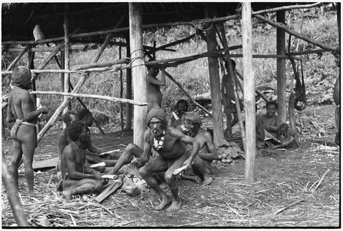 Fainjur: men hold rolled paper, perhaps for cigarettes, man in center smokes