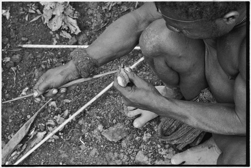 Carving: stone tool being used to smooth an arrow