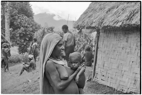 Woman with crescent shell valuable, holds young child